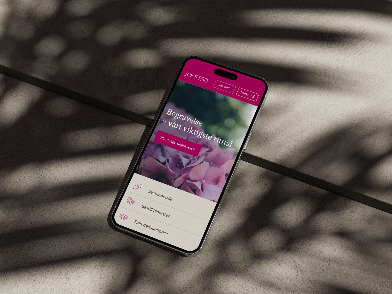 Mobiltelefon som ligger på steinheller med forsiden til Jølstad på skjermen.