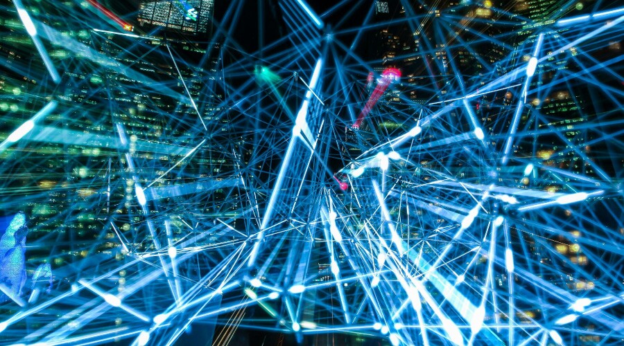 Abstrakt visualisering av et digitalt nettverk med lyslinjer og knutepunkter mot en bakgrunn av bylys om natten.