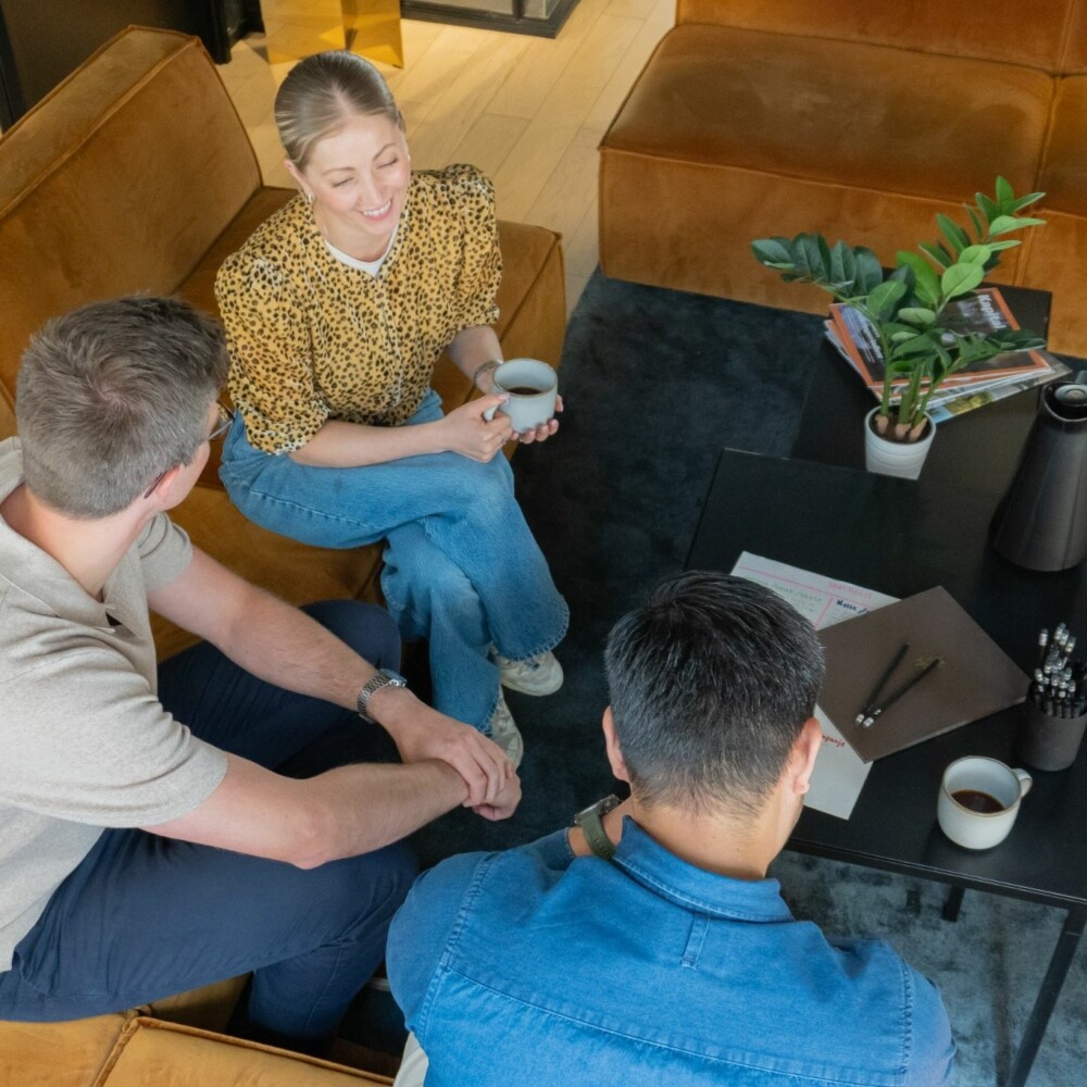 Tre personer som sitter i en sofa og diskuterer markedsføring